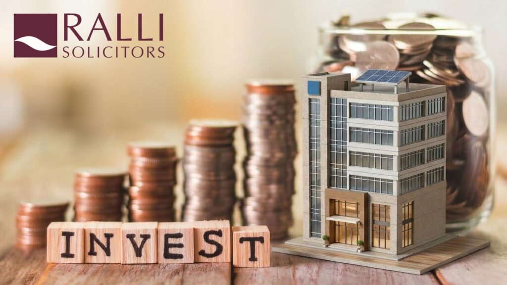 Model commercial property building beside stacks of coins and an investment sign, illustrating property investment and property indemnity insurance.